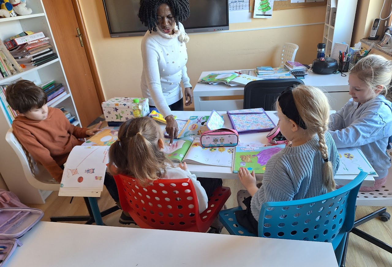 A native-speaker teacher guides a mixed-age group through an English lesson at Open Doors