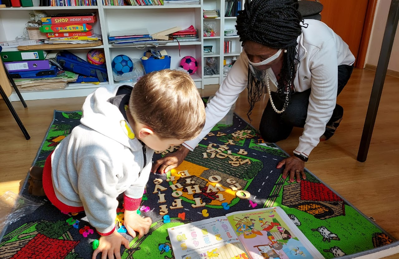 Margaret teaches a toddler English one-on-one on the classroom floor at Open Doors Strzelin